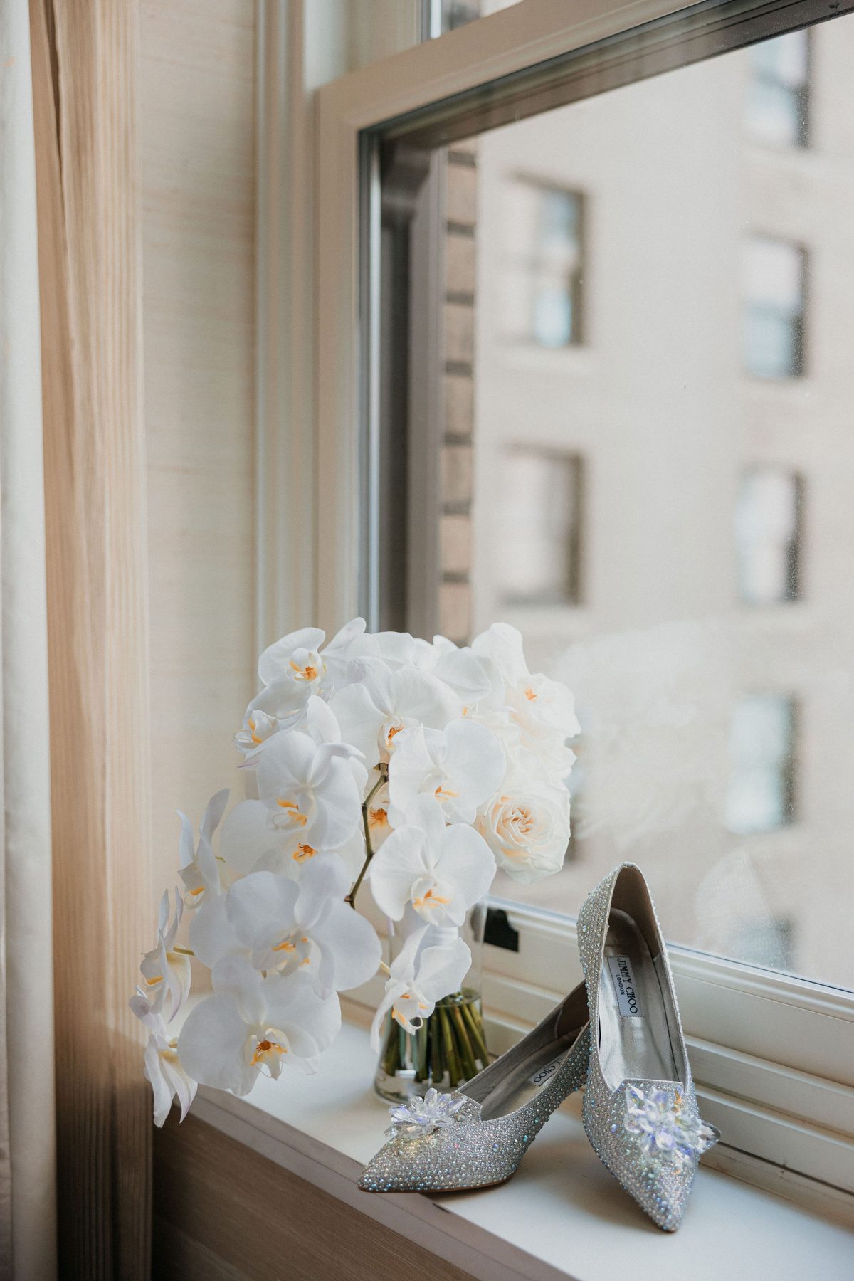 Cascading white orchid bouquet and bridal heels on a hotel windowsill