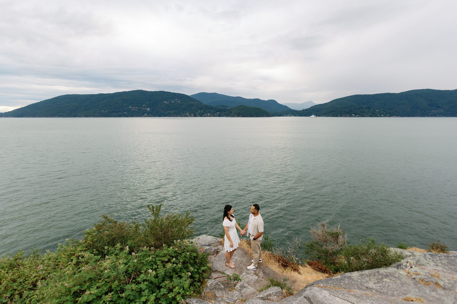 Couple standing on a granite outcrop above Howe Sound at dusk