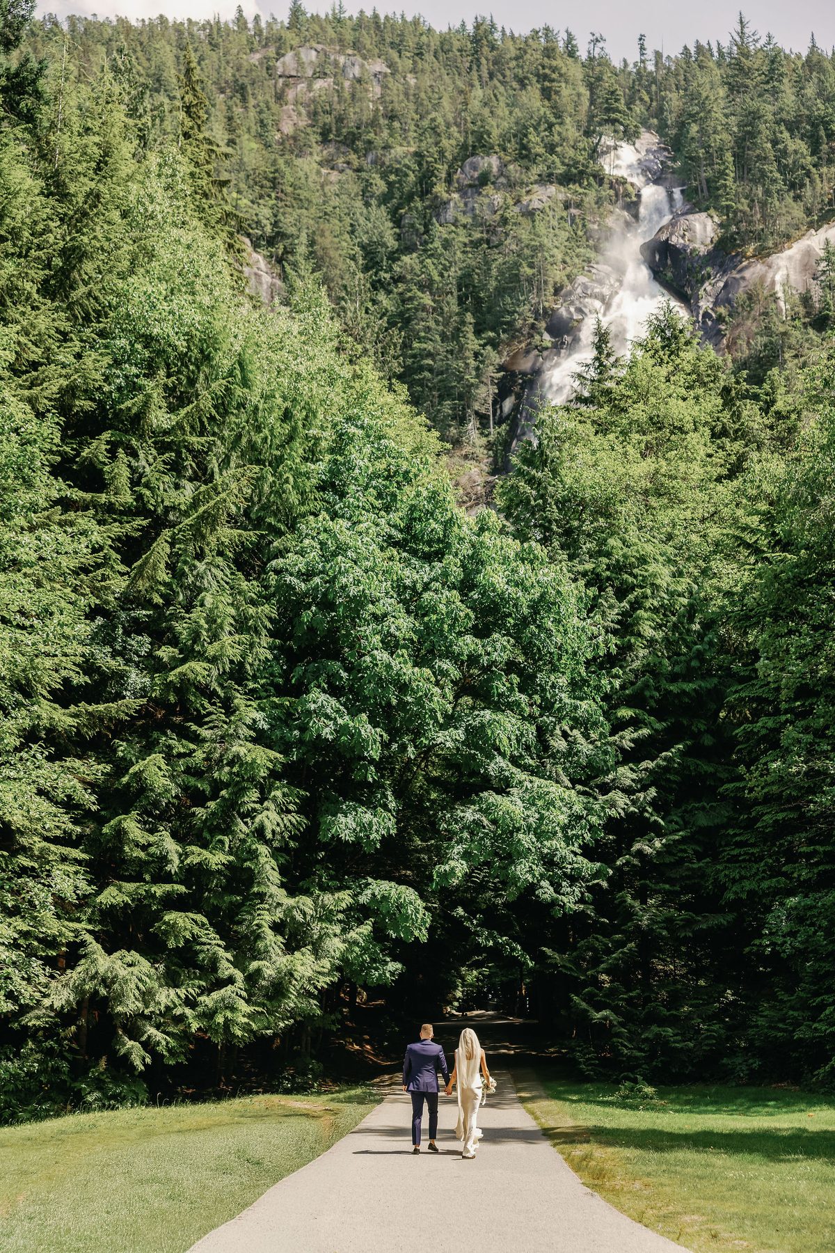 Couple walking a forest trail toward a waterfall in the Sea to Sky corridor