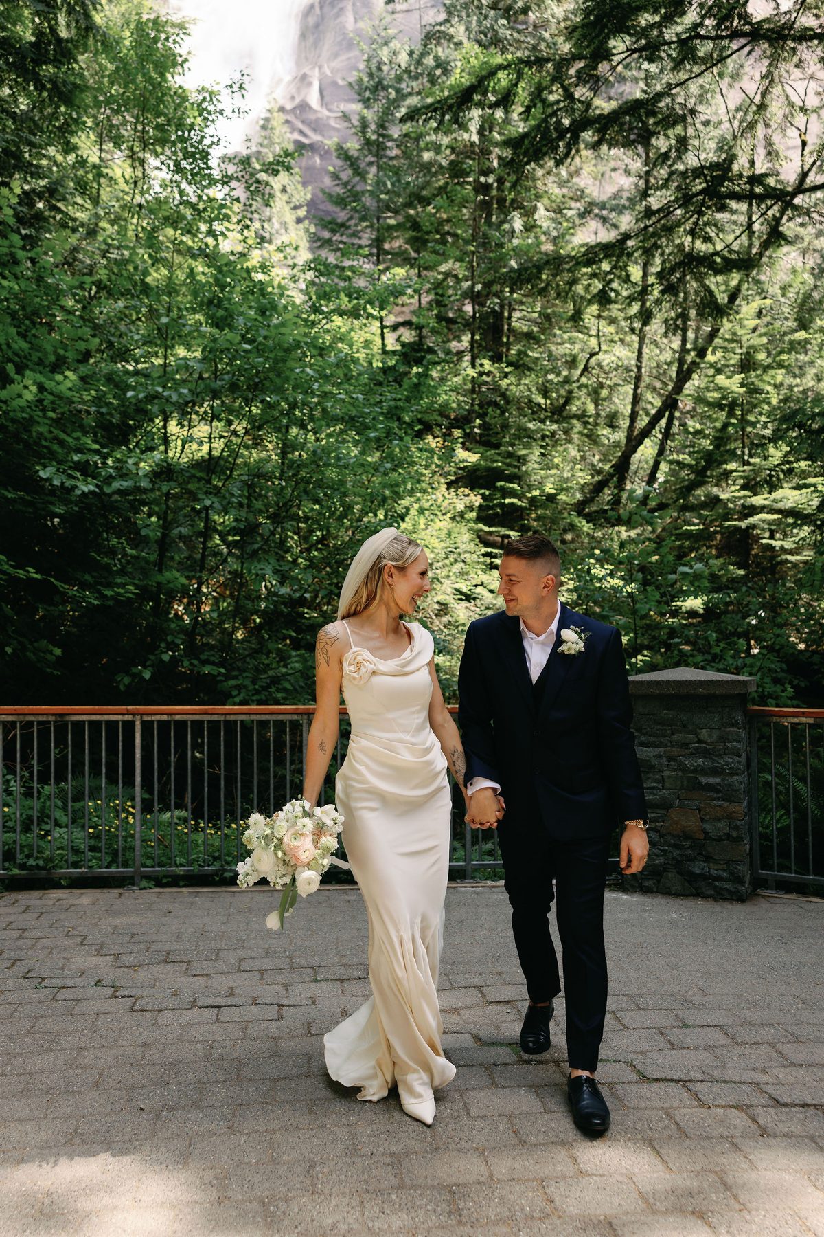 Bride and groom walking hand in hand down a forest path after their ceremony