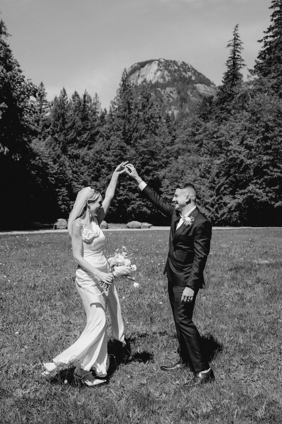Black and white photograph of a bride twirling under her groom's arm