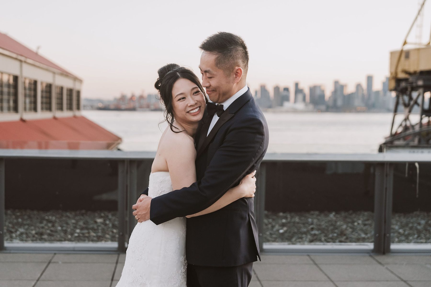 Couple embracing on the terrace at The Wallace with the Vancouver skyline behind them