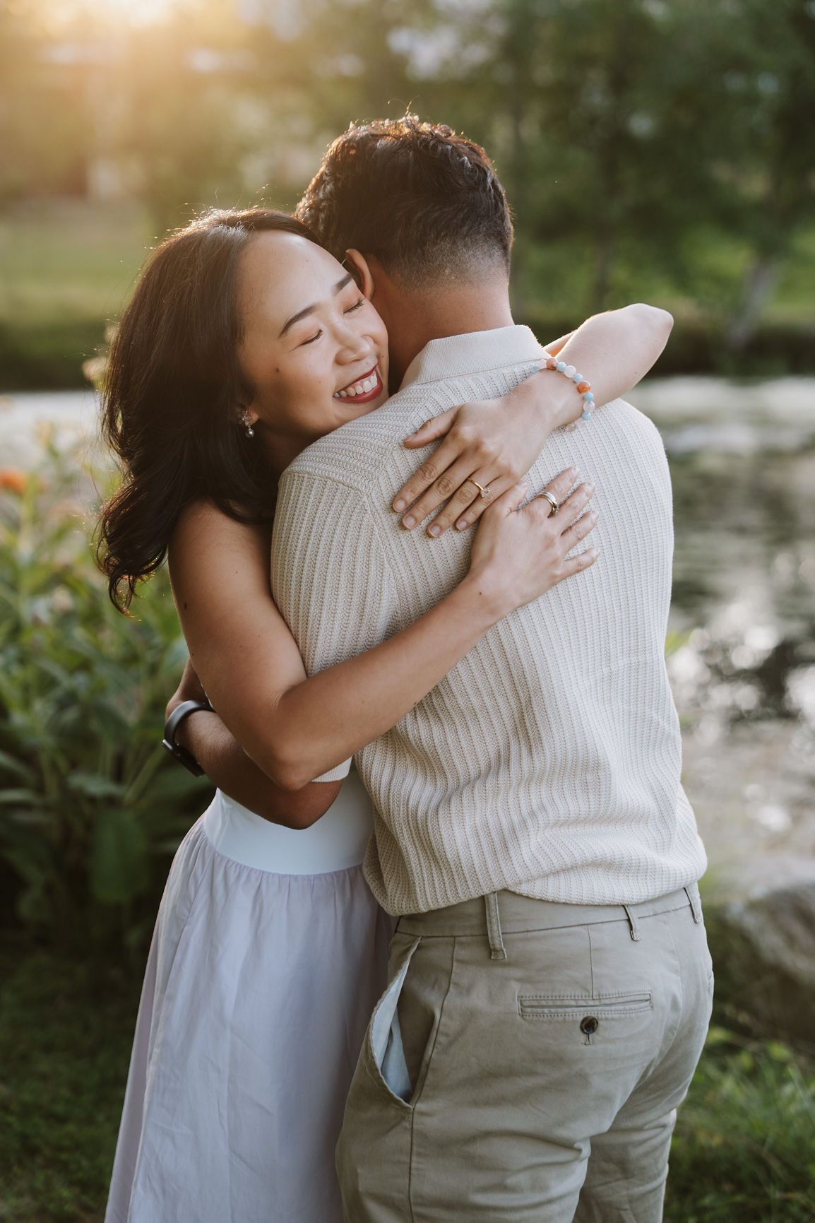 Newly engaged couple holding each other and laughing in a summer field