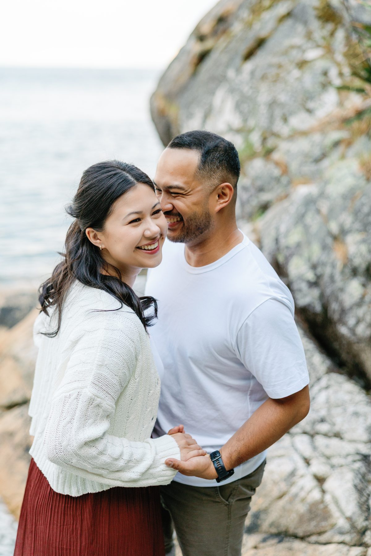Couple holding each other against the rocks on a quiet stretch of coastline