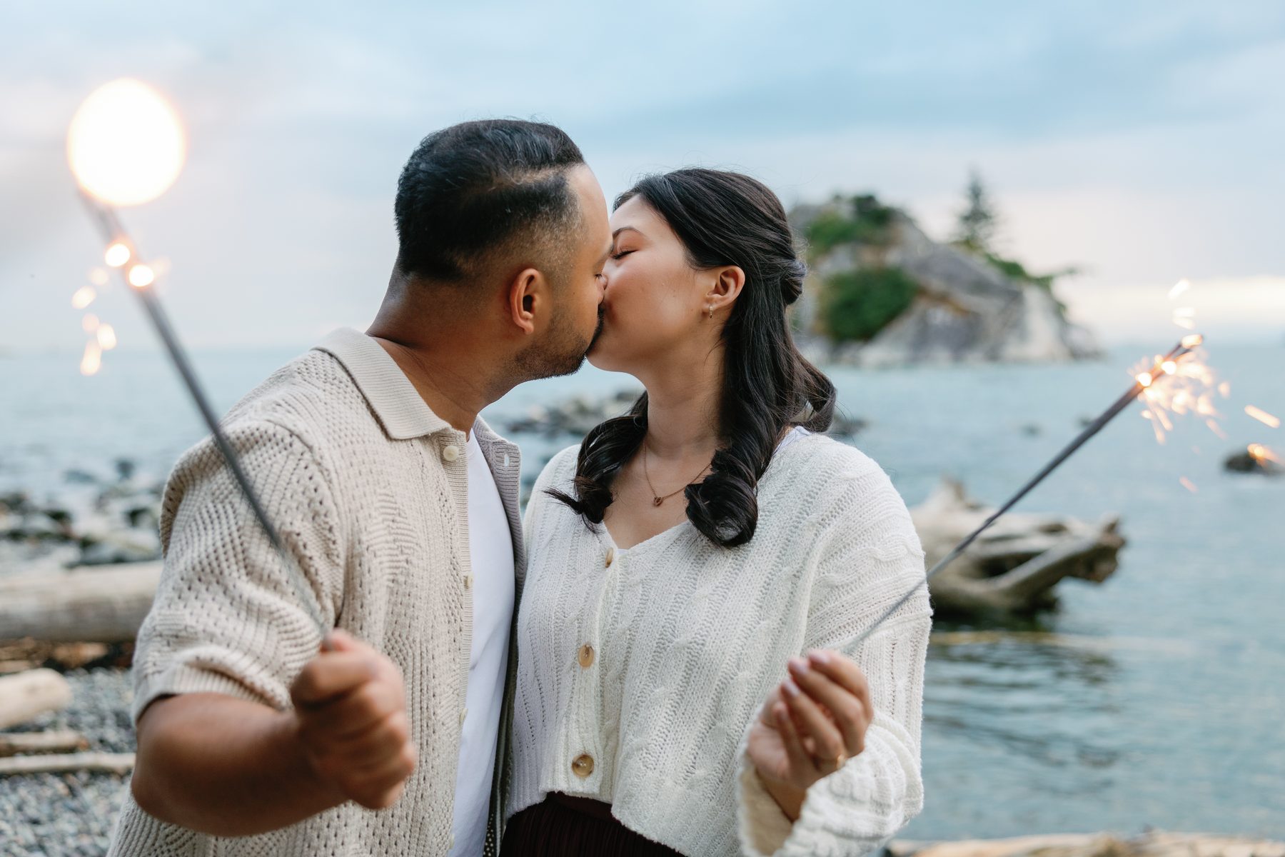 Couple kissing between sparklers on the shore at twilight